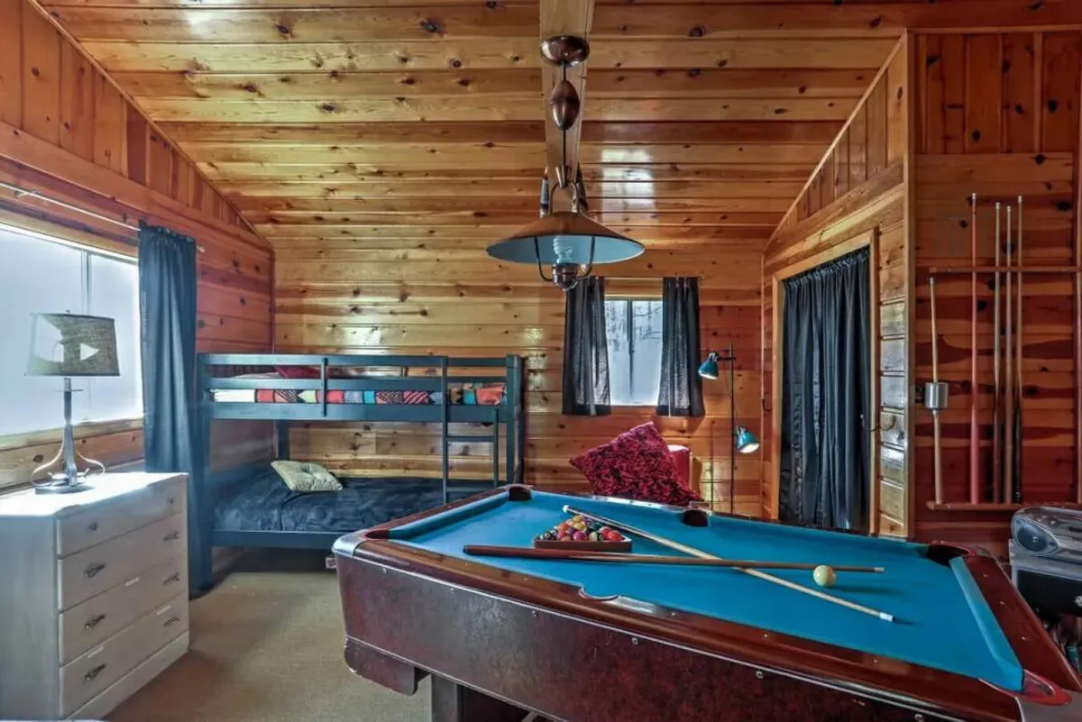 A playful interior scene featuring a pool table, bunk bed, and softly glowing lamps. The area invites friendly competition and makes room for late-night stories and bonding among friends or family.